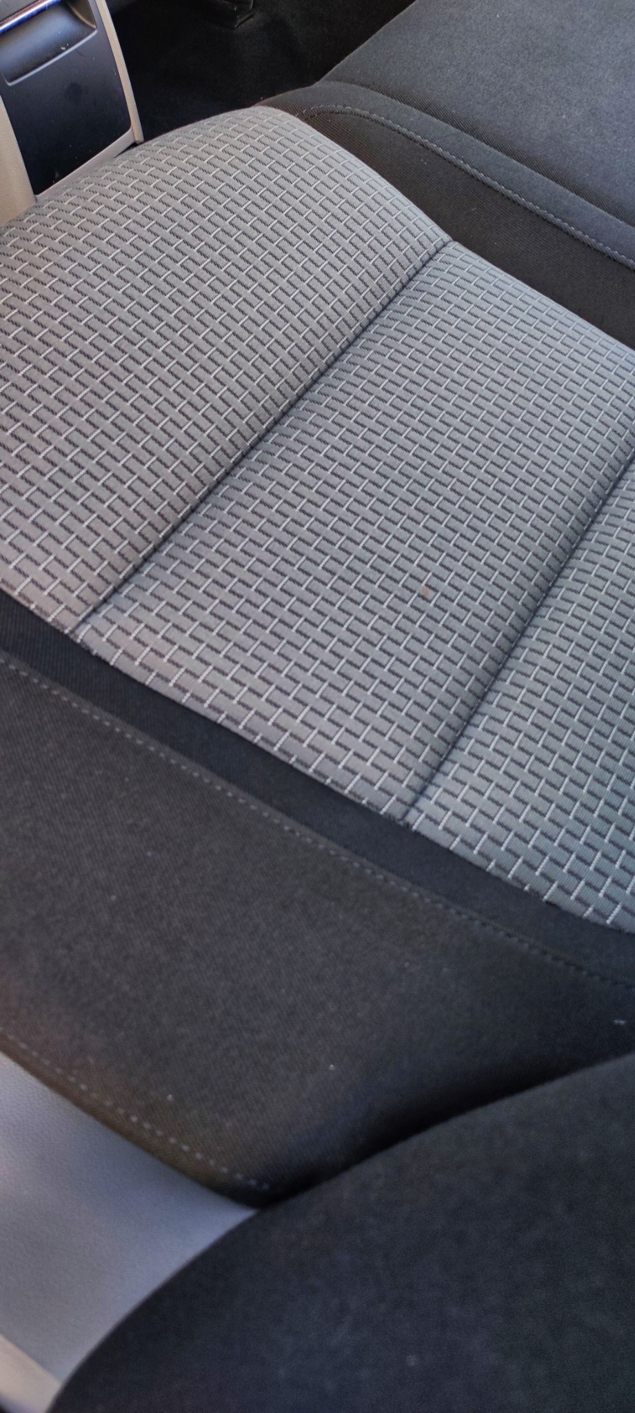 Szare, teksturowane siedzenie samochodowe z widocznym szwem i obiciem.