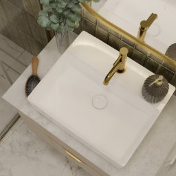 Jotem Studio - Wnętrze łazienki z umywalką nablatową, złotą armaturą, lustrem w złotej ramie i dekoracyjnymi akcentami, takimi jak roślina w szklanym wazonie i dozownik mydła o fasetowanej powierzchni.