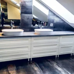 Biała szafka łazienkowa z szarym blatem i dwiema owalnymi umywalkami w nowoczesnej łazience na poddaszu z oknem dachowym.