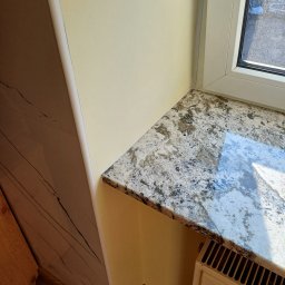 Huliailo Dmytro - Parapet z konglomeratu w odcieniach szarości, zamontowany w jasnym wnętrzu, z widocznym grzejnikiem i fragmentem drewnianej podłogi.