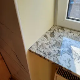 Parapet z konglomeratu w odcieniach szarości, zamontowany w jasnym wnętrzu, z widocznym grzejnikiem i fragmentem drewnianej podłogi.