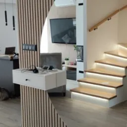 Nowoczesne wnętrze z drewnianą ścianką działową z lamelami, półką z szufladami i podświetlanymi schodami drewnianymi.