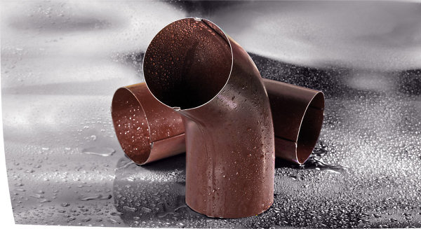 Dwa brązowe kolanka rynnowe z tworzywa sztucznego, pokryte kroplami wody, na błyszczącym, mokrym tle.
