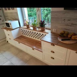 OL-BUD Oleksiak Bogusław - Kuchnia z frontami lakierowanymi, z lakierowaną kratką jako osłona grzejnika i blat drewniany lakierowany.