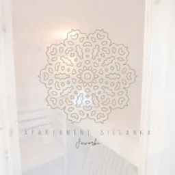 Wnętrze sauny z drewnianym wykończeniem, nałożony graficzny ornament w kształcie śnieżynki i napis 'Apartament Sielanka Jaworki'.