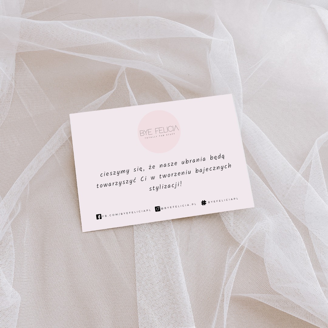 Różowa wizytówka firmy odzieżowej BYE FELICIA na tle delikatnej, białej tkaniny. Wizytówka zawiera tekst: 'Cieszymy się, że nasze ubrania będą towarzyszyć Ci w tworzeniu bajecznych stylizacji!'...