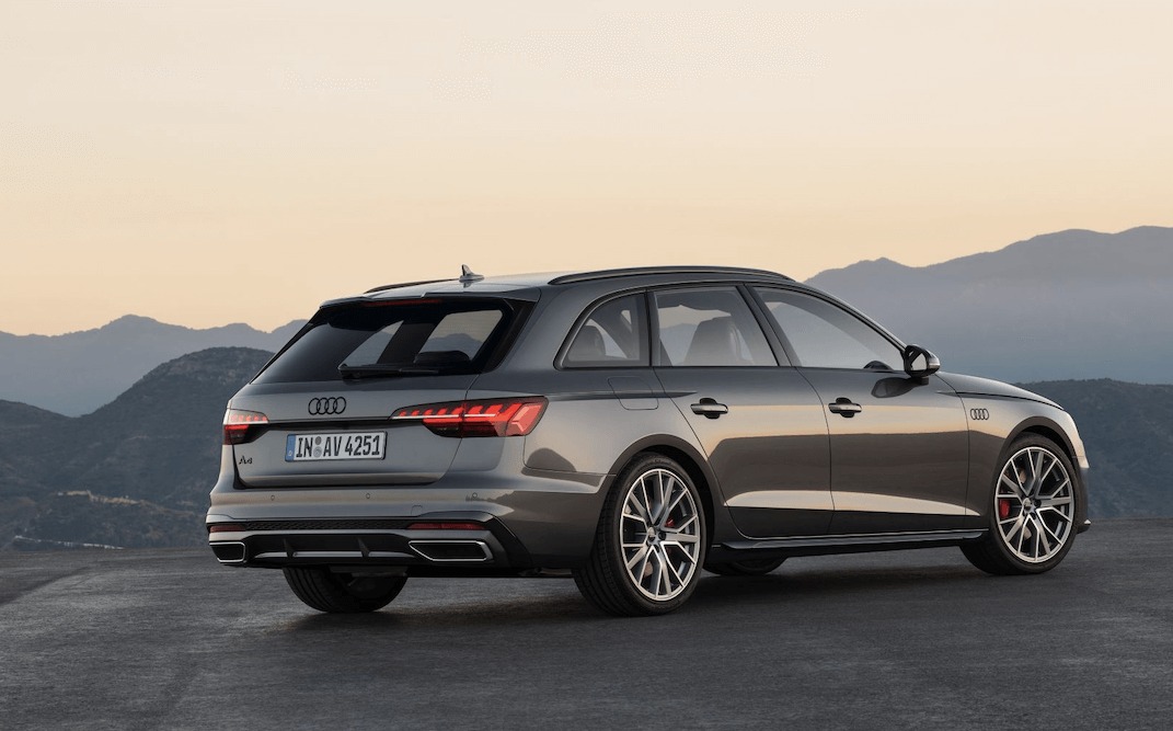 Szary samochód Audi A4 Avant, widok z tyłu, na tle gór o zmierzchu, z widocznymi detalami jak felgi i tablica rejestracyjna.