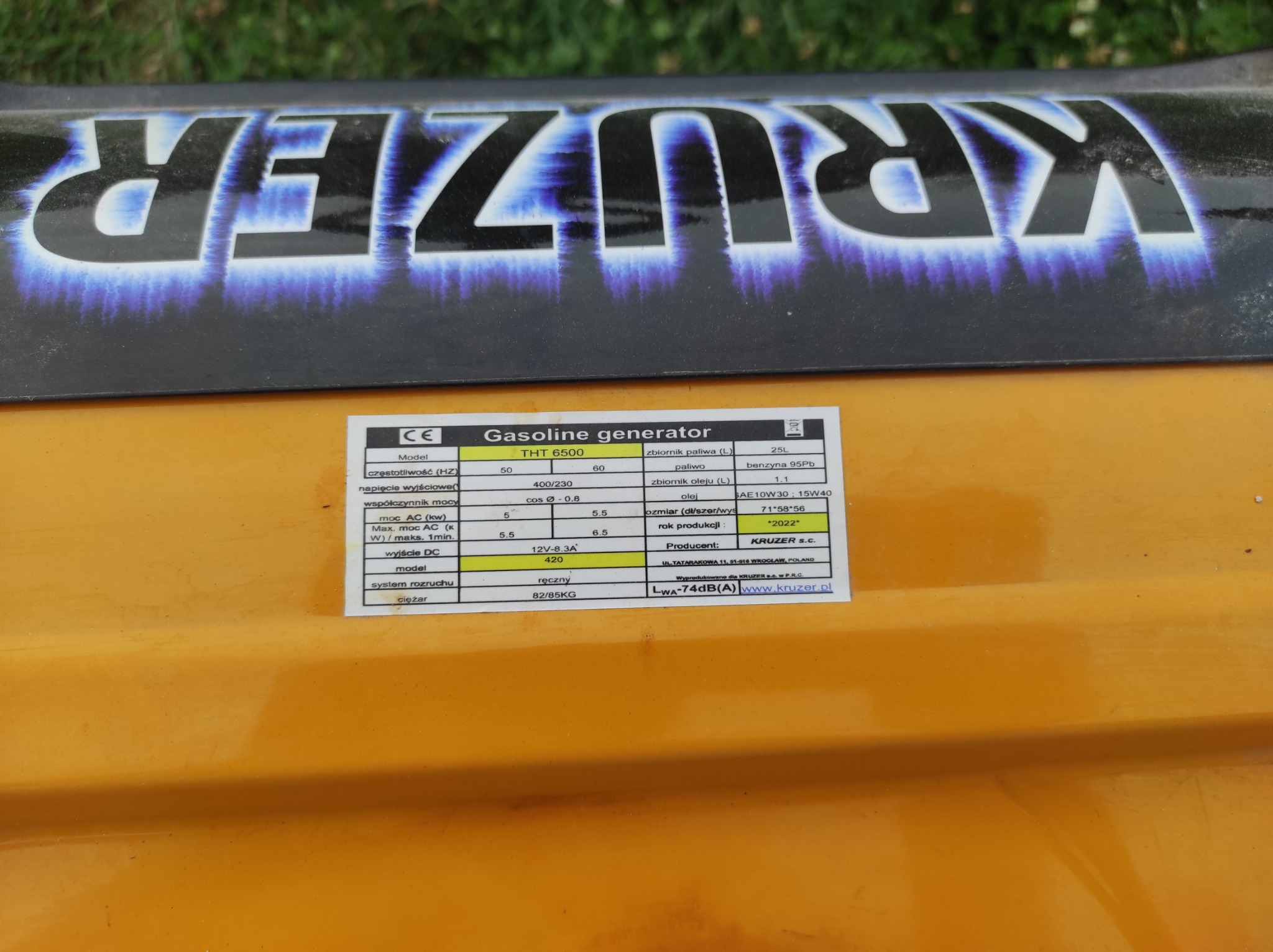Tabliczka znamionowa agregatu prądotwórczego KRUZER THT 6500, z widocznymi parametrami technicznymi, takimi jak moc, napięcie, pojemność zbiornika paliwa i oleju, rok produkcji 2022 oraz adres...