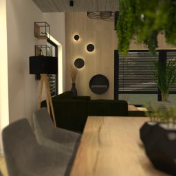 MODERN STUDIO W.FIRLEJ, M.FIRLEJ Spółka cywilna - Wizualizacja salonu z drewnianym stołem, zieloną sofą i dekoracyjną ścianą z okrągłymi lampami, uzupełniona o rośliny doniczkowe i lampę podłogową na trójnogu.