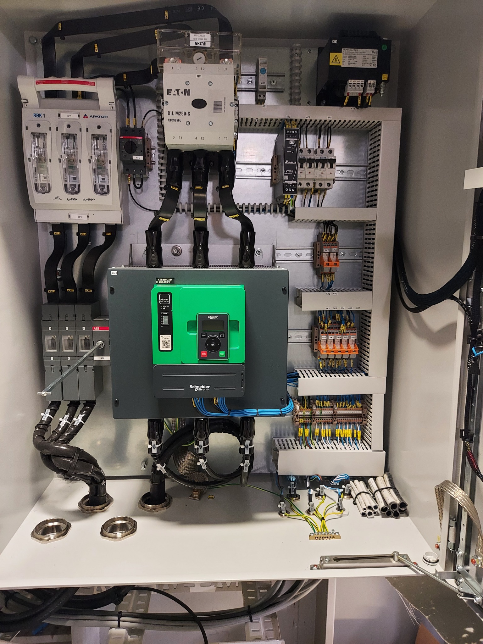 Rozdzielnica elektryczna z elementami zabezpieczeń, wyłącznikami, stycznikami i okablowaniem wewnątrz metalowej obudowy, widoczne komponenty firm Eaton, ABB i Schneider Electric.