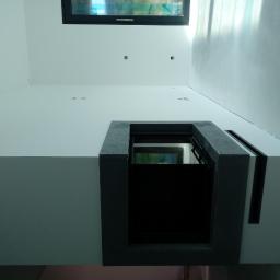 B&F Kompleksowe Wykończenia Wnętrz - Wnętrze po malowaniu z oknem dachowym i elementami architektonicznymi w szarym betonie, widok z dołu.