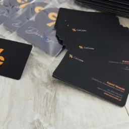 Stos wizytówek firmy CarCulate, doradcy ds. finansowania pojazdów, obok zawieszek zapachowych z logo i napisem 'Dziękuję'.