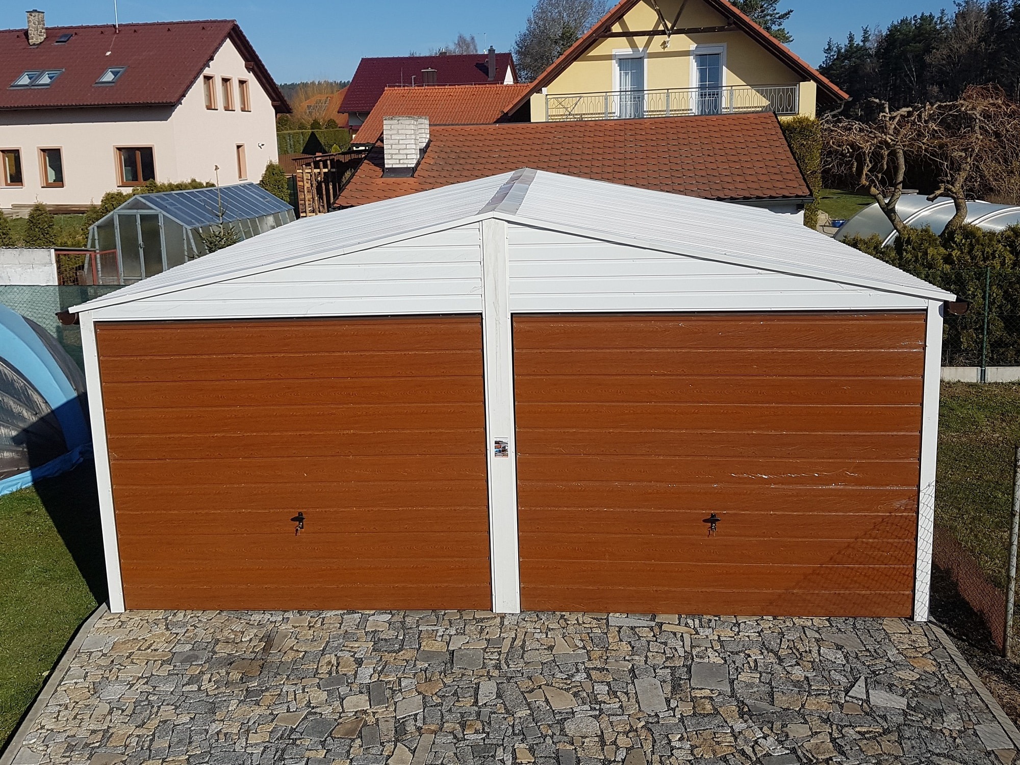 Biała konstrukcja garażowa, świetnie wpisująca się w otoczenie