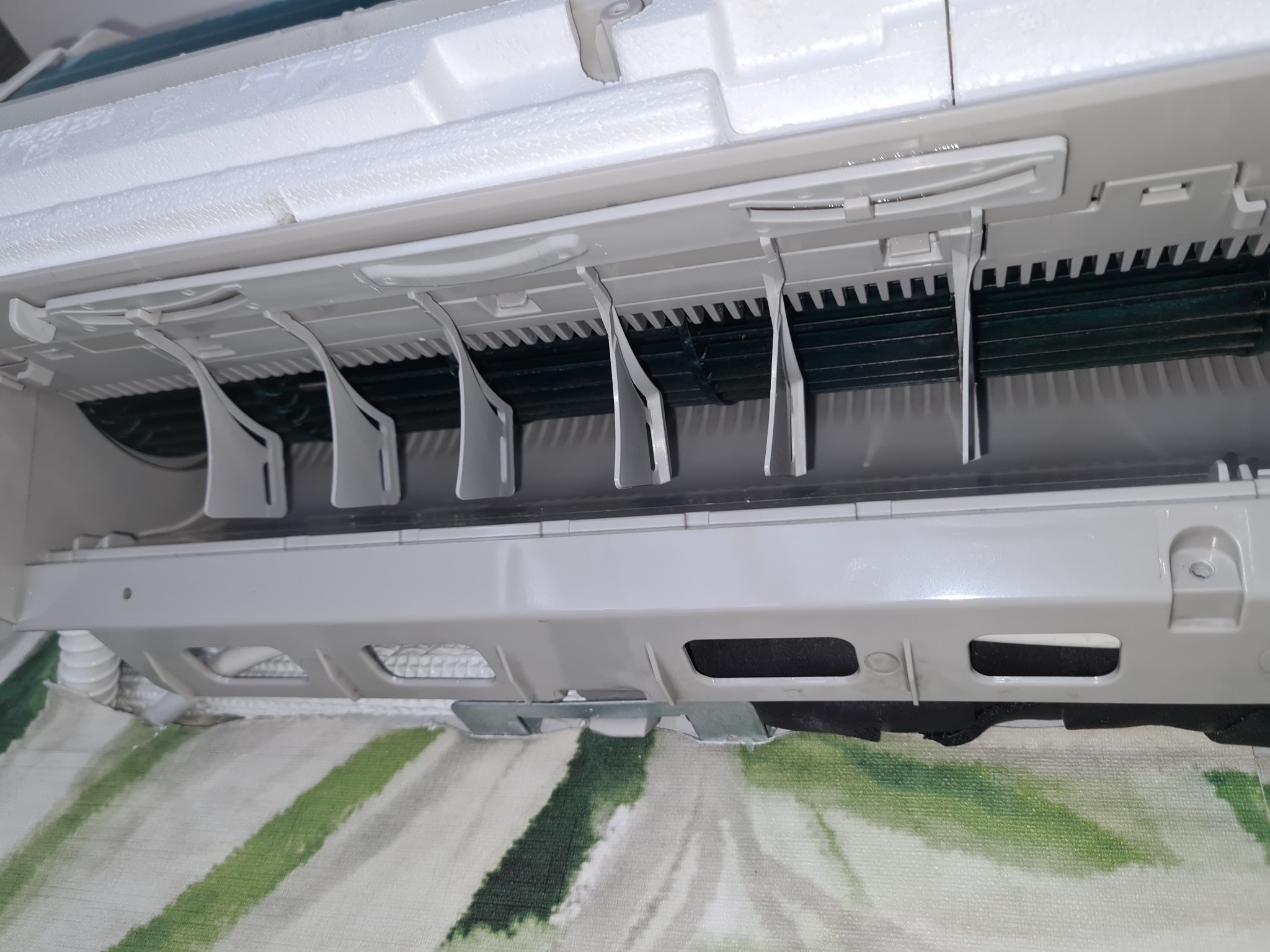 Wnętrze klimatyzatora ściennego z widocznymi filtrami i żaluzjami, prawdopodobnie podczas czyszczenia lub serwisu.