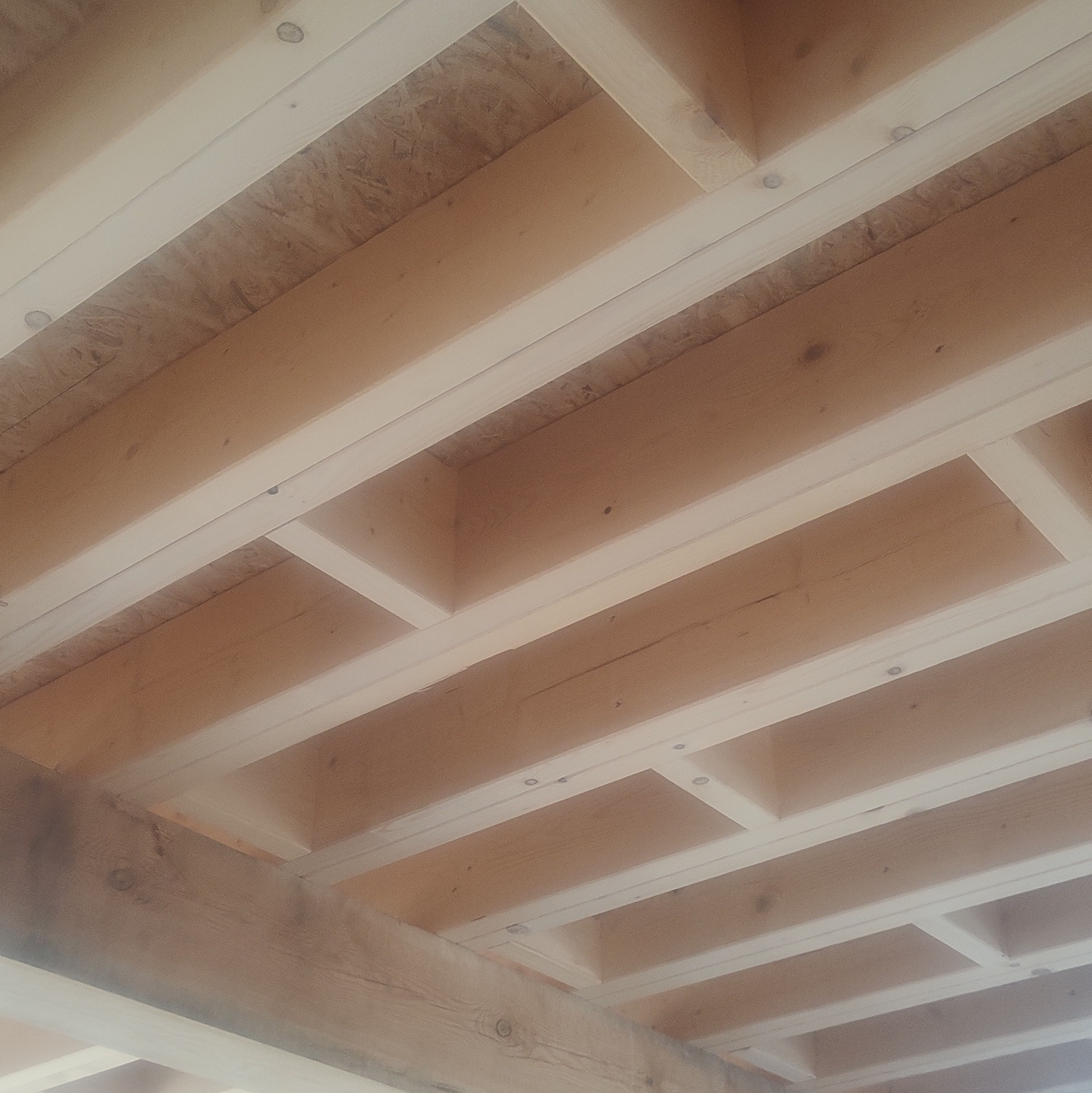 Drewniana konstrukcja stropu z belek i desek, widok z dołu, jasne drewno, surowy stan, przygotowanie do dalszych prac wykończeniowych.