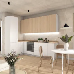 Jasna kuchnia z drewnianymi szafkami wiszącymi, białymi szafkami dolnymi, okrągłym białym stołem i plecionymi krzesłami, oświetlona lampami sufitowymi i listwą LED pod szafkami, z dekoracyjnymi...