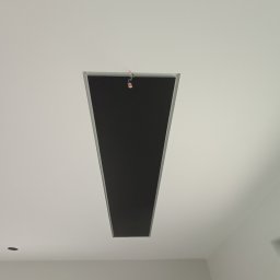 Pro Standard Bartłomiej Miczołek - Prostokątny otwór w suficie, prawdopodobnie przygotowany pod montaż oświetlenia, z wystającymi przewodami elektrycznymi, widok z dołu.