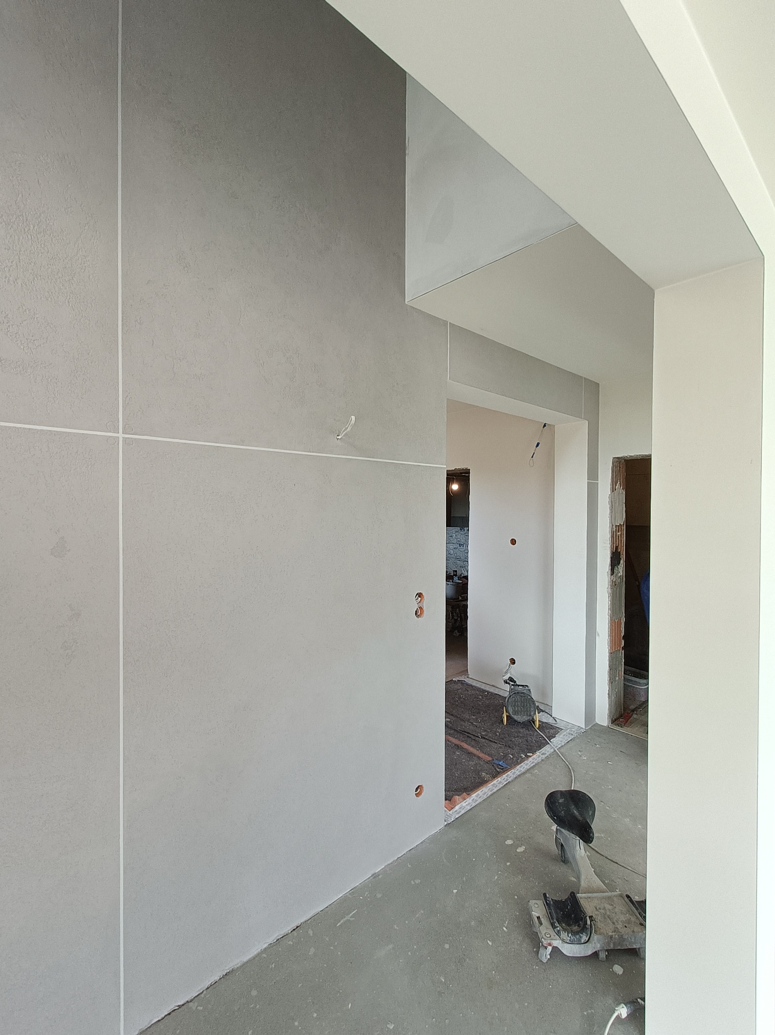 Ściana z płyt kartonowo-gipsowych z widocznymi łączeniami w nowym budownictwie w Nowym Sączu, na podłodze widoczny sprzęt budowlany.