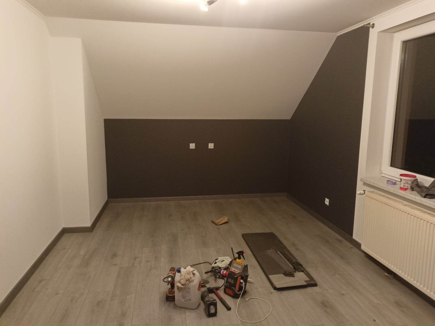 Pokój po malowaniu w Łapanowie, ściany częściowo w kolorze czekoladowym, widoczne narzędzia malarskie i listwa przypodłogowa.