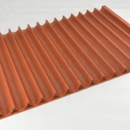 Pomarańczowa, perforowana forma do pieczenia bagietek, widoczna z perspektywy ukośnej na białym tle.