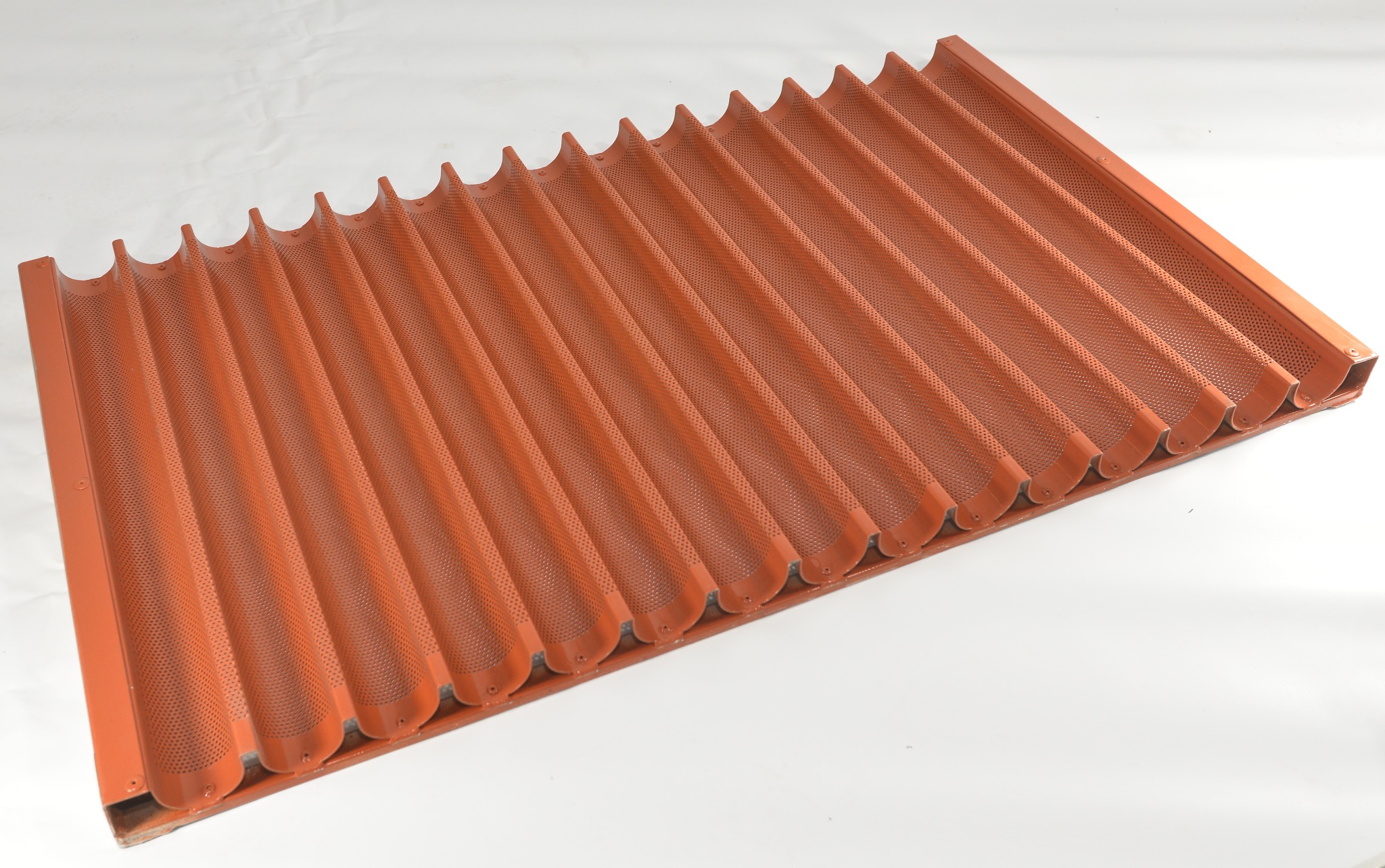 Pomarańczowa, perforowana forma do pieczenia bagietek, widoczna z perspektywy ukośnej na białym tle.