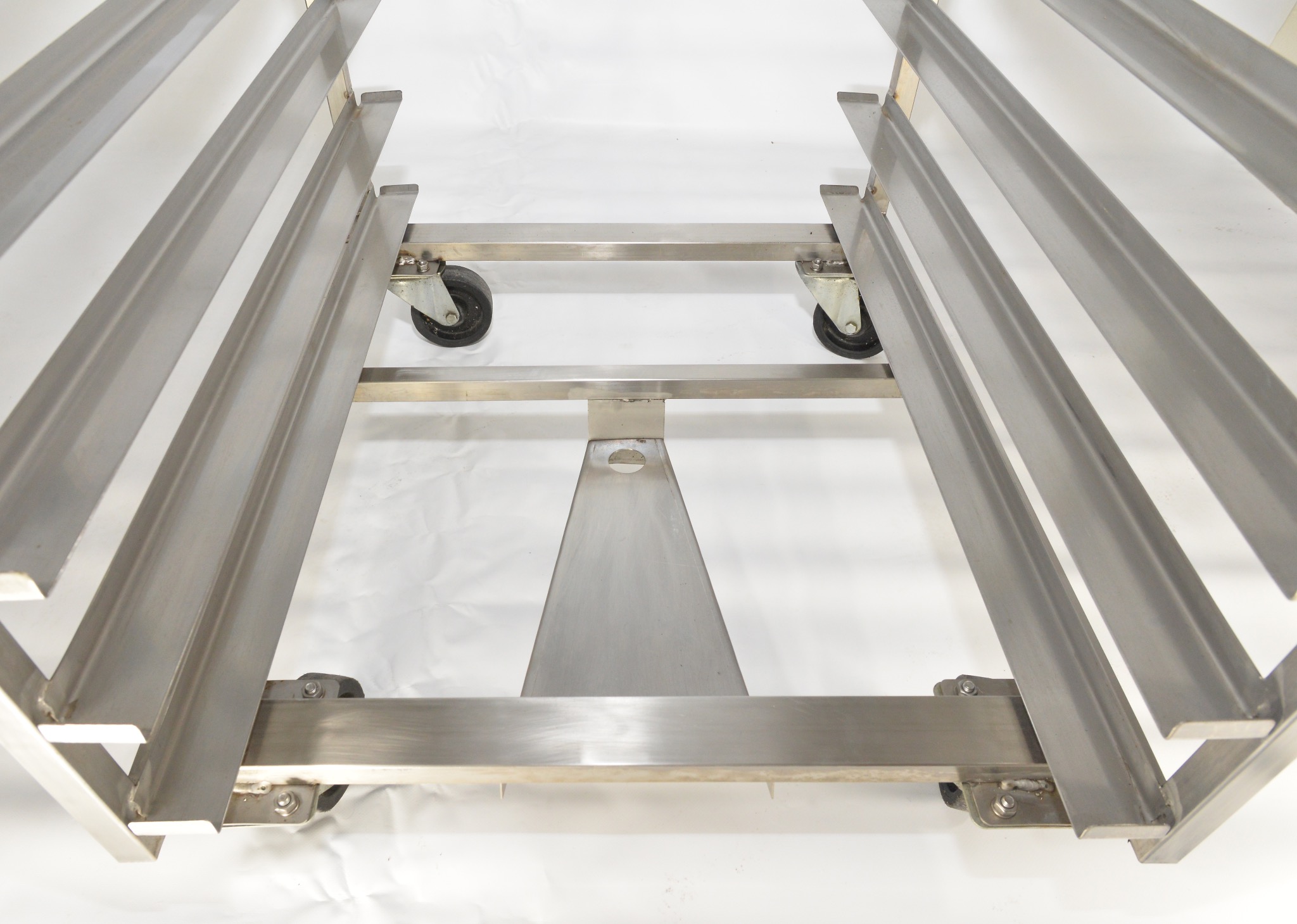 Metalowy wózek transportowy z kółkami, wykonany ze stali nierdzewnej, widok z góry na białym tle.