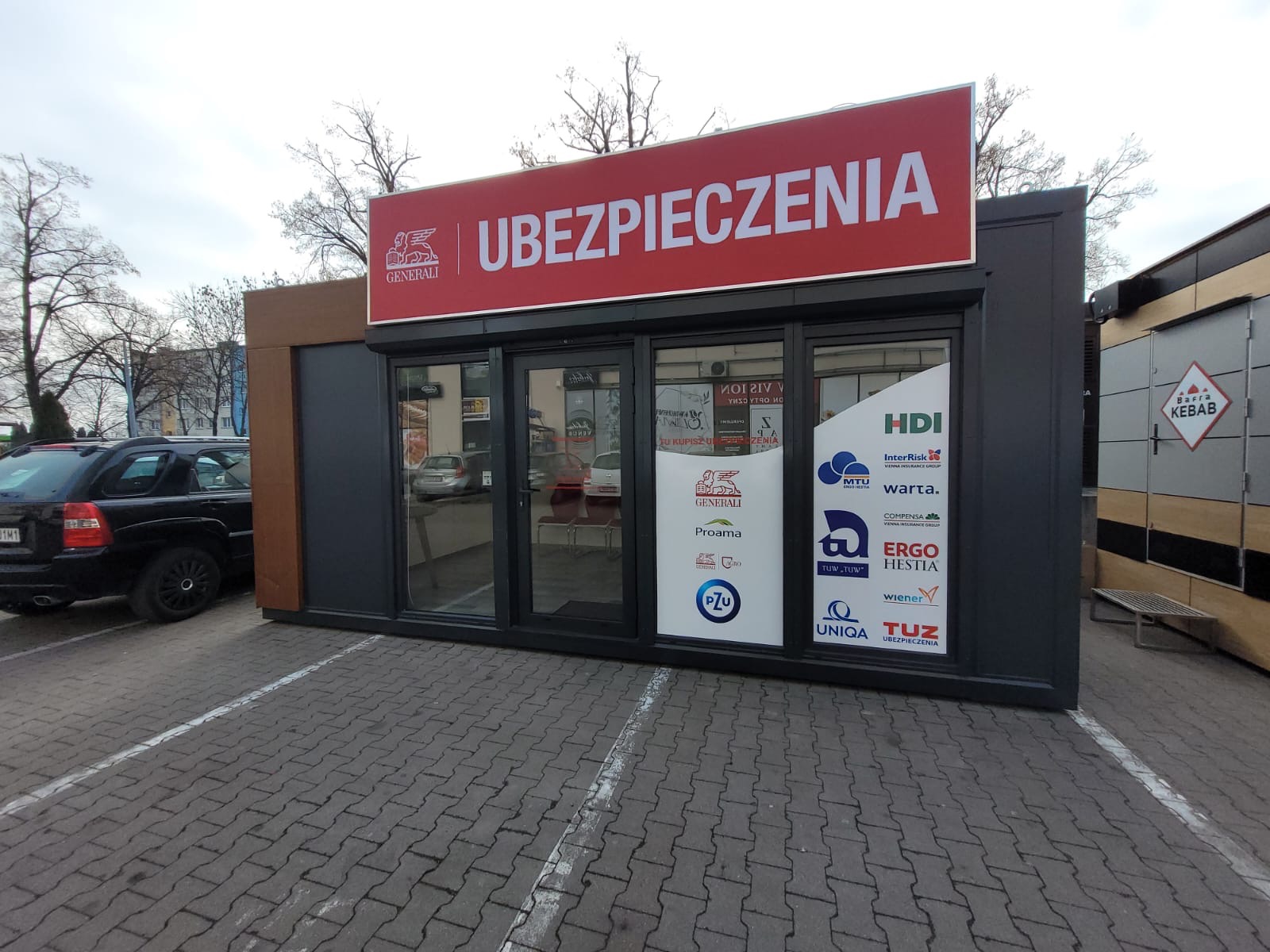 Biuro ubezpieczeń Generali w Brzegu, z widocznymi logotypami innych towarzystw ubezpieczeniowych na szybach.