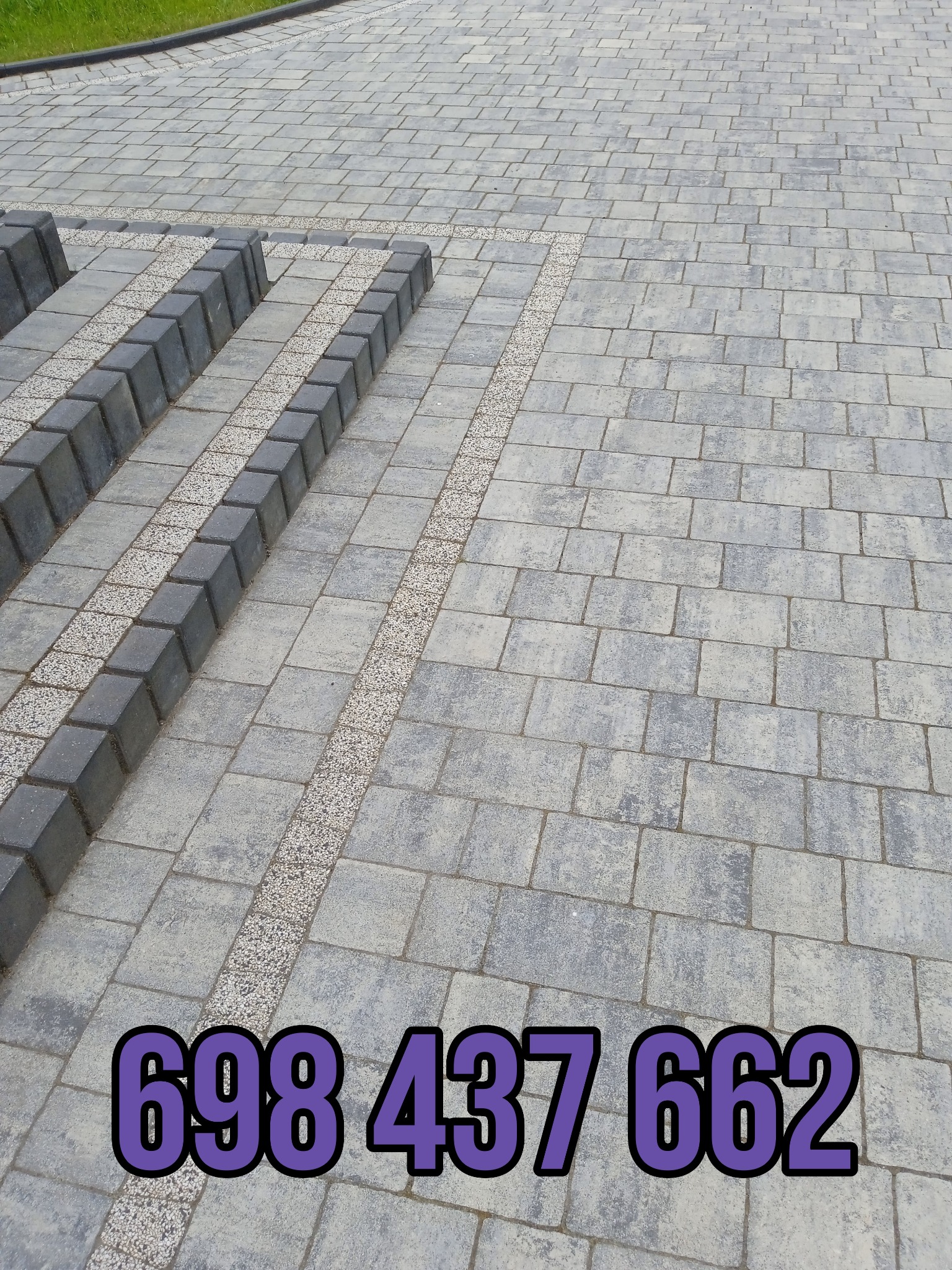 Szara kostka brukowa ułożona w regularny wzór z obramowaniem z ciemniejszych kostek i jasnego żwiru; w prawym dolnym rogu widoczny numer telefonu.