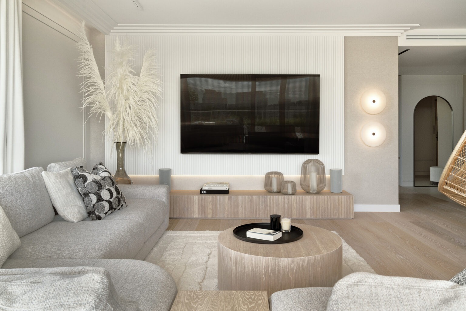 Jasny salon z szarą sofą, telewizorem na ścianie z panelami, okrągłym stolikiem kawowym i dekoracyjnymi lampami ściennymi.