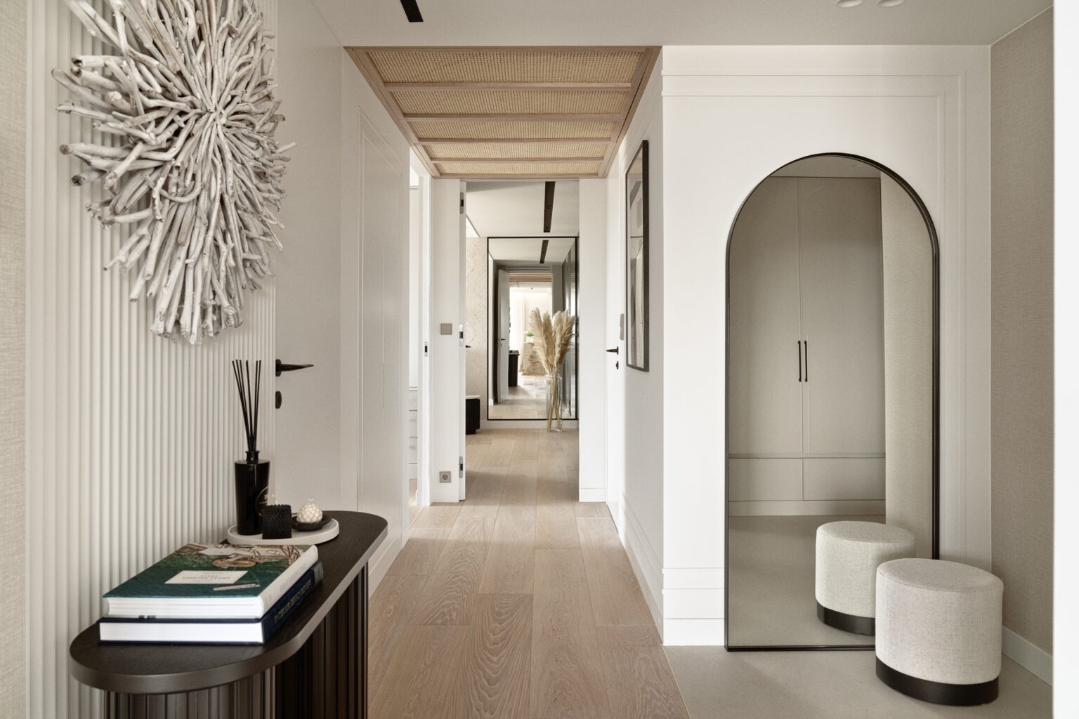 Nowoczesny przedpokój z drewnianą podłogą, dekoracyjnym sufitem z plecionki, dużym lustrem w łukowej ramie i ozdobą ścienną z gałęzi.