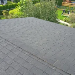 Nowy, czarny dach z gontów bitumicznych w Tychach, widok z góry na tle zielonego ogrodu z placem zabaw.