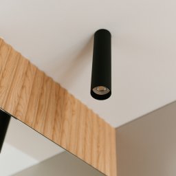 Pracownia Architektury Wnętrz - Abstracto - Minimalistyczna łazienka: czarna lampa sufitowa tuba nad lustrem z drewnianą ramą. Nowoczesne oświetlenie punktowe w jasnym wnętrzu.