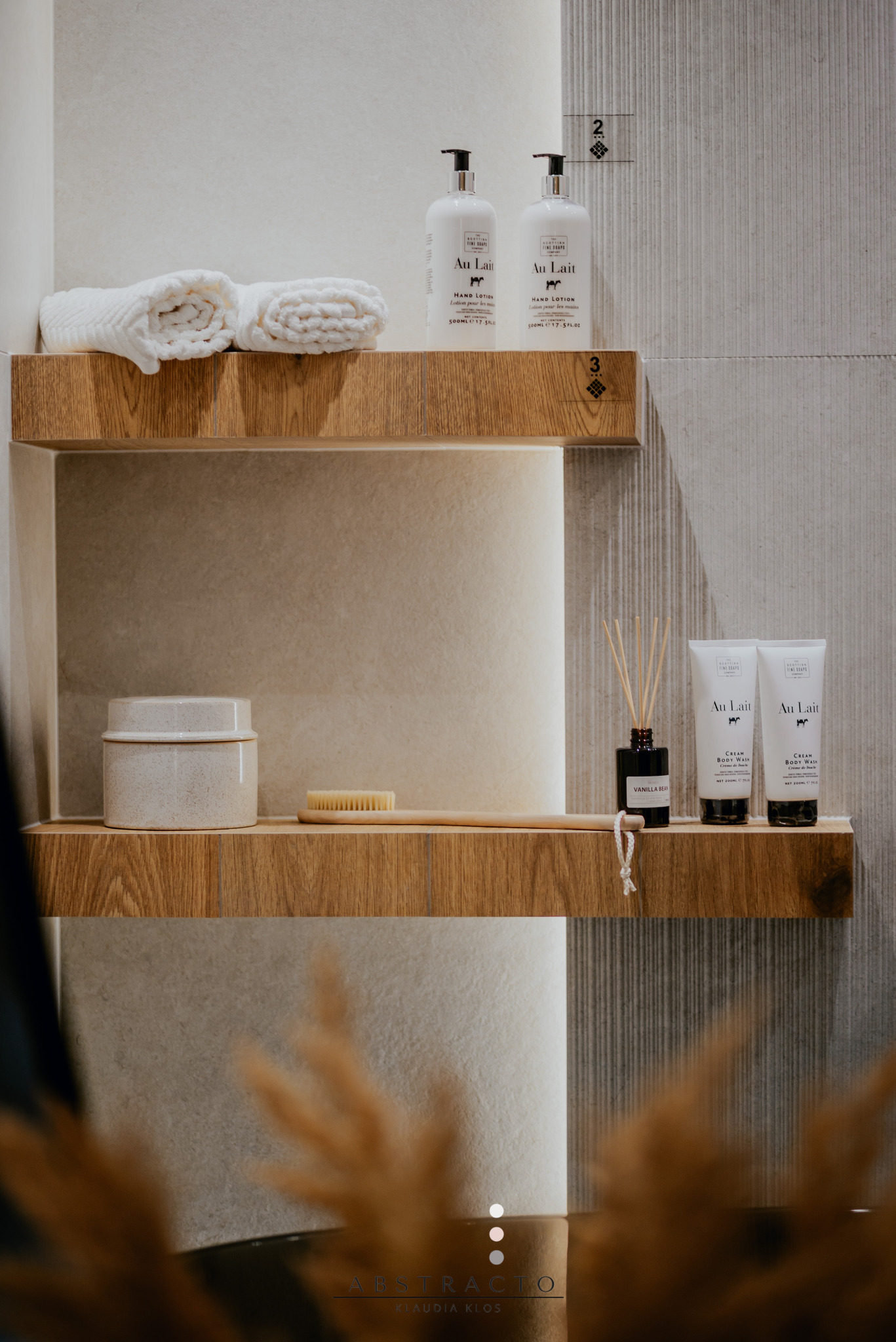 Minimalistyczna łazienka z drewnianymi półkami, na których stoją kosmetyki i ręczniki, oświetlona delikatnym światłem, tworząc przytulną atmosferę.