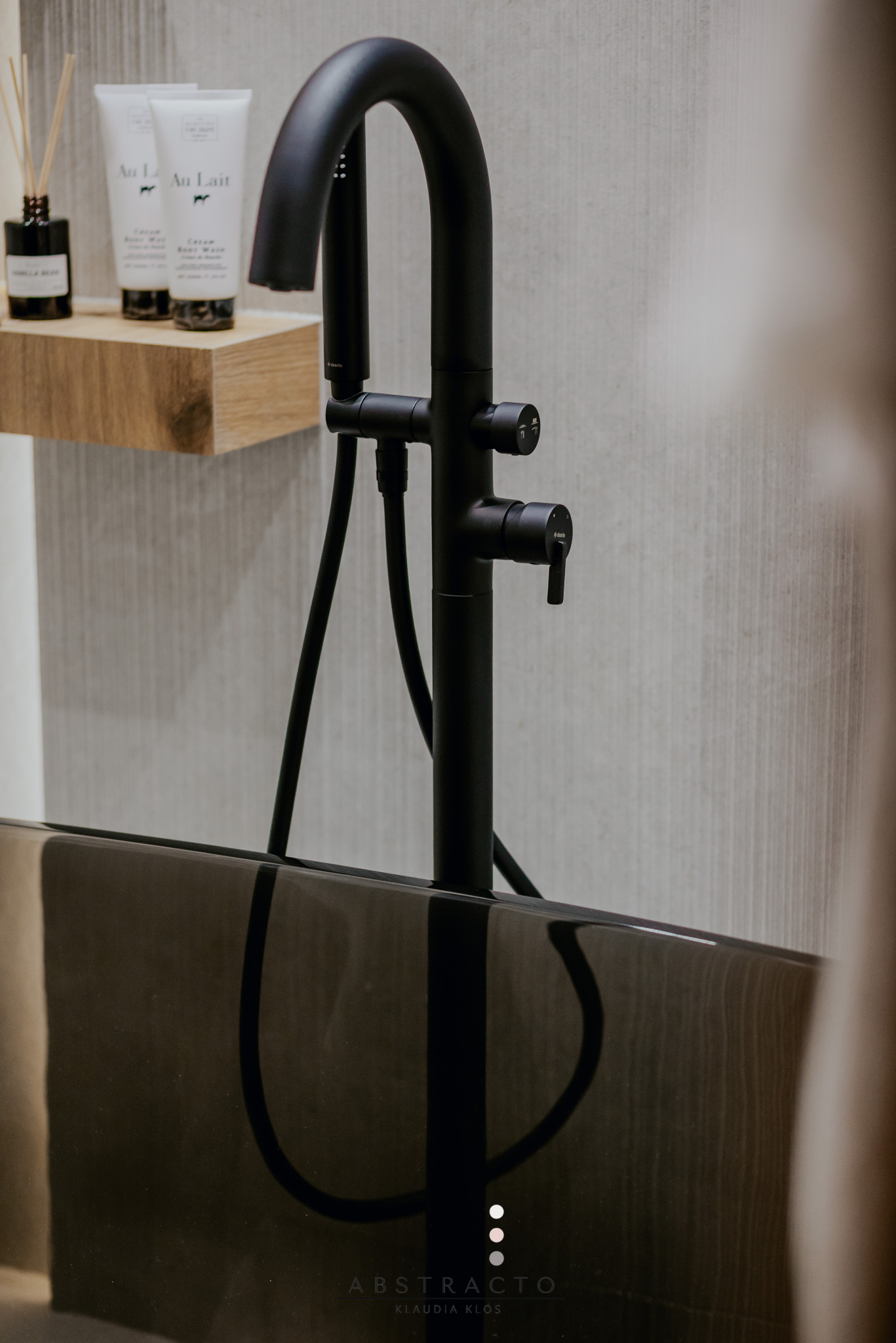 Czarna bateria wannowa, minimalistyczna półka z kosmetykami 'Au Lait', elegancka wanna. Detal projektu łazienki, nowoczesny design.