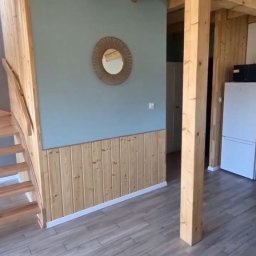 APOLLO ANDRII ZINCHENKO - Wykończenie wnętrza: drewniane panele ścienne, szare płytki podłogowe, drewniane schody i strop, okrągłe lustro na niebieskiej ścianie. Nowoczesny design.