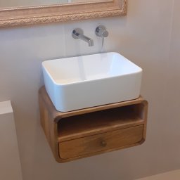 APOLLO ANDRII ZINCHENKO - Nowoczesna łazienka: biała, prostokątna umywalka nablatowa na drewnianej szafce z szufladą, srebrna bateria ścienna, lustro w zdobionej ramie.