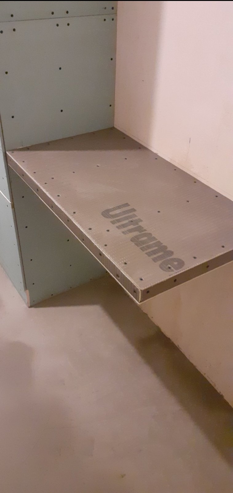 Płyta Ultrament zamocowana na ścianie z płyt gipsowo-kartonowych, przygotowana do wykończenia w łazience.