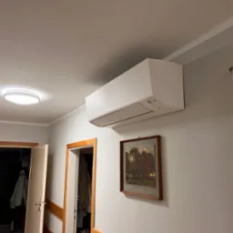 Zamontowana jednostka klimatyzacji Daikin na ścianie w mieszkaniu w Olsztynie, widoczny obrazek w ramie i otwarte drzwi do innego pomieszczenia.