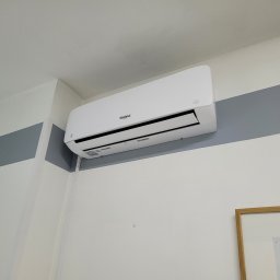 AK Serwis - Biały klimatyzator Whirlpool zamontowany na ścianie z szarym pasem, widoczny fragment obrazu w ramie.