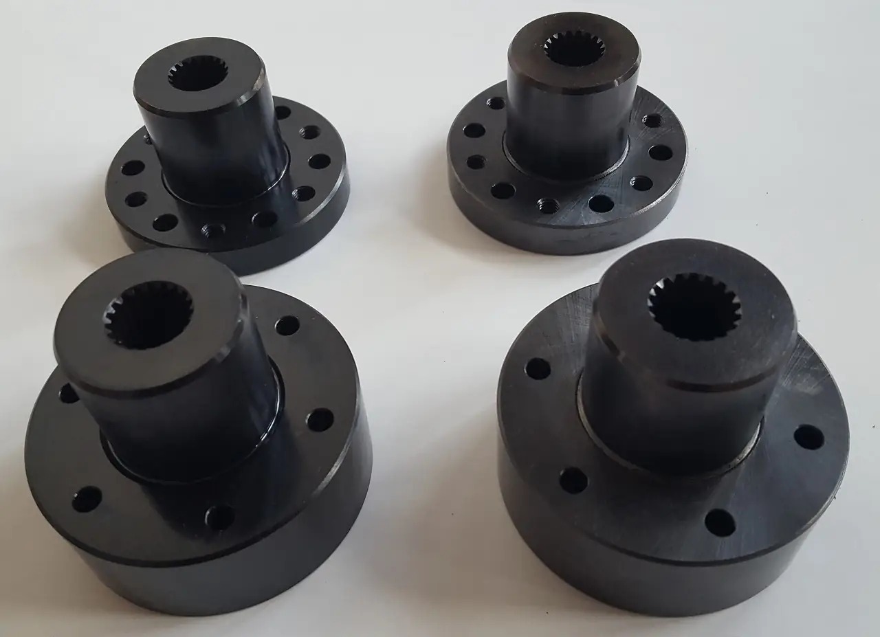 Cztery czarne, metalowe kołnierze z otworem wielowypustowym w środku, ułożone na białym tle. Widoczne otwory montażowe na obwodzie kołnierza.