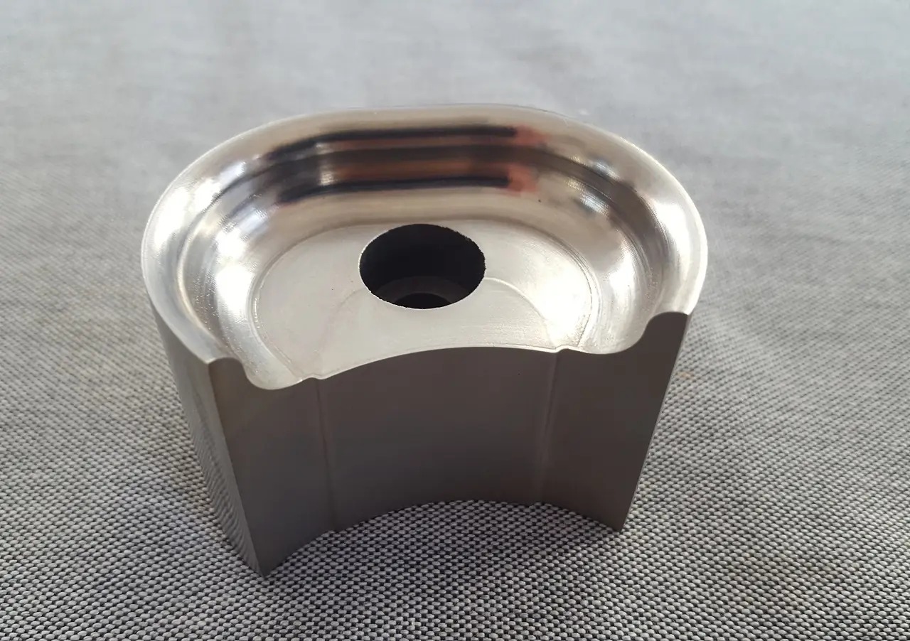 Precyzyjnie obrobiony, metalowy element z otworem centralnym, widoczne ślady obróbki CNC i wysoki połysk powierzchni.