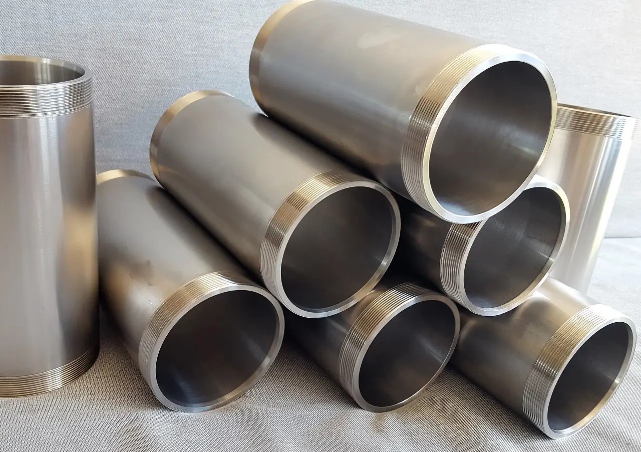 Zestaw gładkich, metalowych rur z gwintowanymi końcami, ułożonych na szarym tle, ukazujących precyzyjną obróbkę.