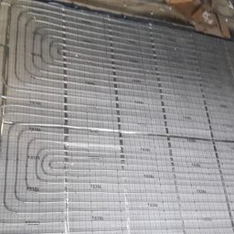 Berben - Instalacja rur systemu grzewczego podłogowego na izolacji z nadrukowaną siatką i oznaczeniami TECE, widok z góry, surowy stan przed wylewką.