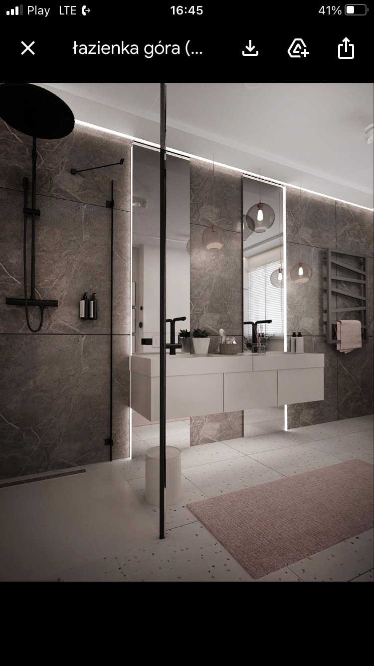 Nowoczesna łazienka z szarymi marmurowymi płytkami, czarną armaturą, podświetlanymi lustrami i beżowym dywanikiem na podłodze z terazzo.