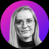 Portret młodej kobiety z blond włosami na tle gradientu różowo-fioletowego. Zdjęcie czarno-białe z wyjątkiem tła. Uśmiech delikatny, wzrok skierowany wprost.