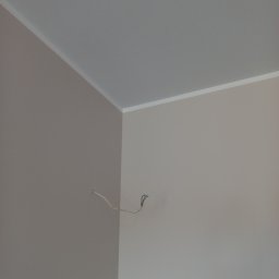 Kamil Małysza - Pomieszczenie po malowaniu ścian na dwa odcienie beżu z białym wykończeniem sufitu i wystającymi przewodami elektrycznymi.