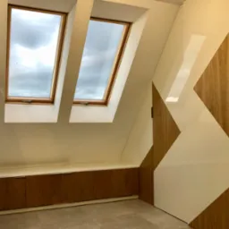 Adaptacja poddasza: zabudowa z szafkami pod oknami dachowymi, ściana z geometrycznym wzorem drewna i bieli, neutralna kolorystyka wnętrza.