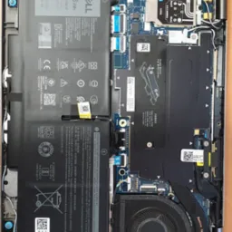 Wnętrze laptopa Dell po demontażu obudowy, widoczna bateria, płyta główna, wentylator i inne komponenty. Przegląd serwisowy komputera w Raciborzu.