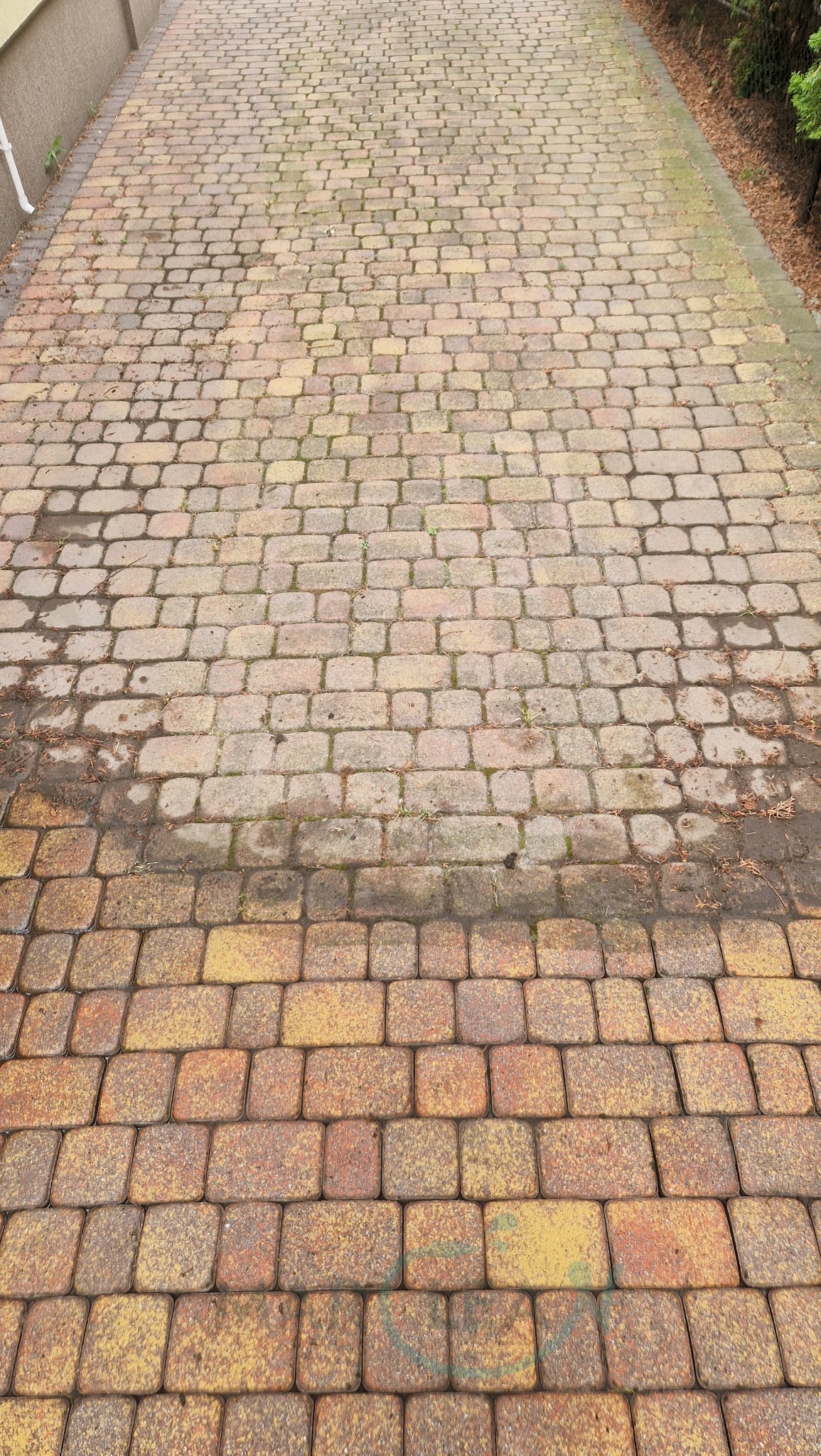 Kostka brukowa: dolna część po czyszczeniu, górna - przed. Widoczne różnice w kolorze i czystości. Perspektywa z góry, długa ścieżka.