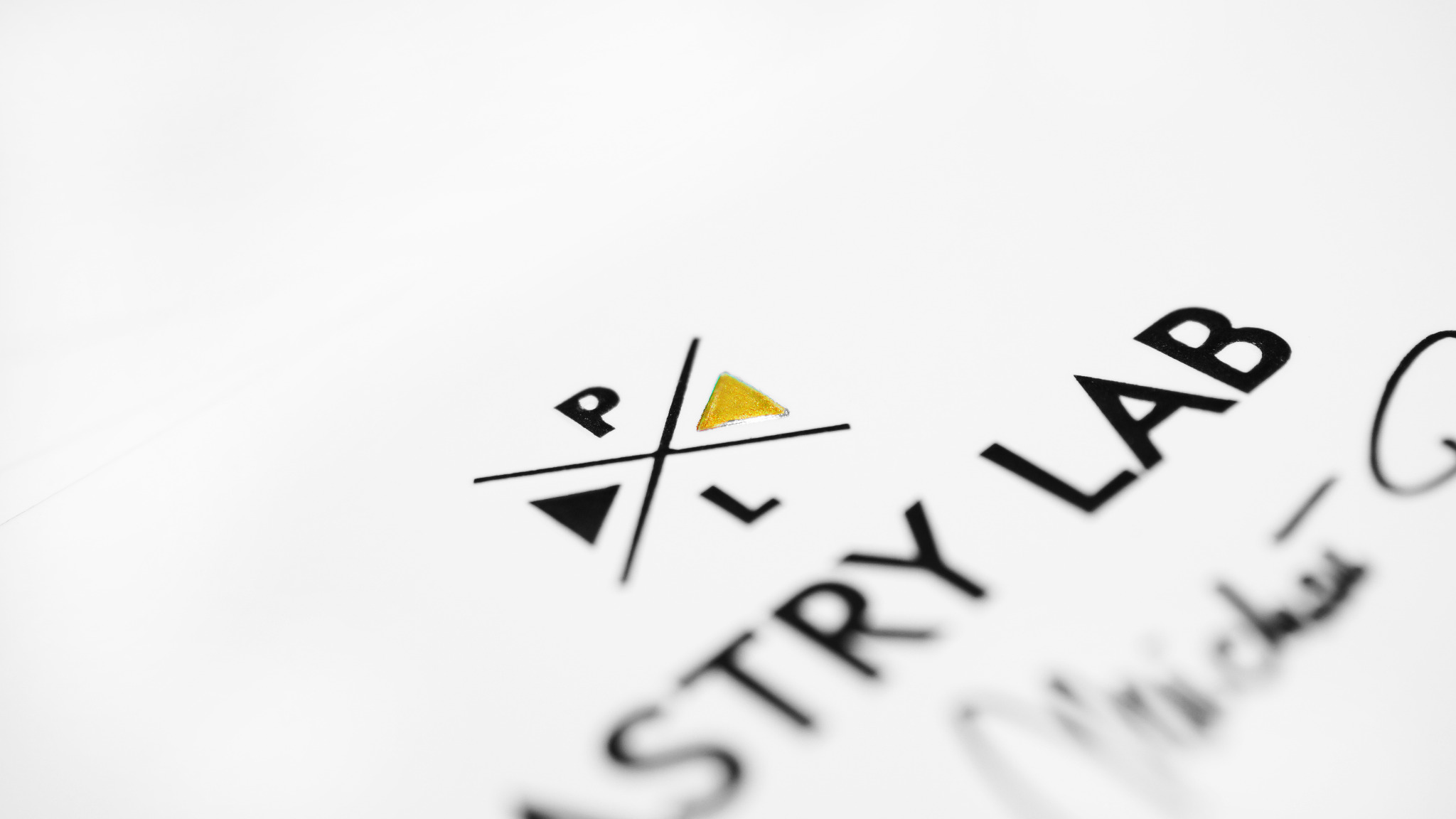 Minimalistyczne logo 'PL ASTRY LAB' z złotym trójkątem na białym tle, częściowo rozmyte.